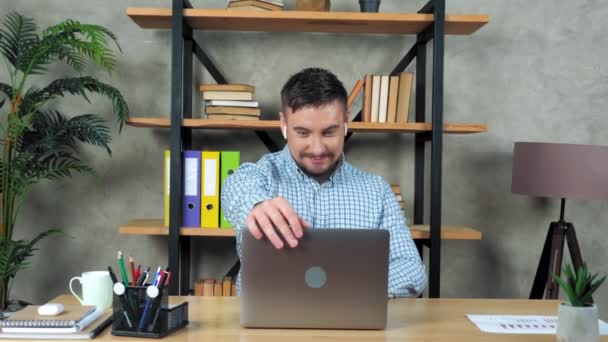 笑顔のビジネスマンは、自宅のオフィスで机の上に座っているラップトップを使用して起動します - 映像、動画