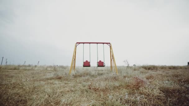 Empty swing in the field. Abandoned city. Desolate playground. Deserted place. Sad childhood memories. Apocalypse. Devastation. Horror. - Footage, Video