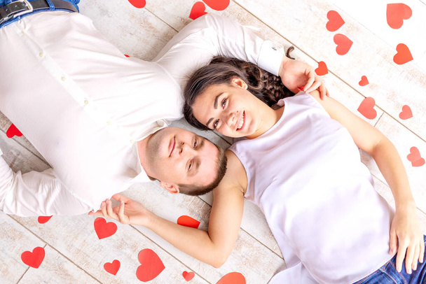 Dia dos Namorados, um casal apaixonado está entre os corações no chão abraçando - Foto, Imagem