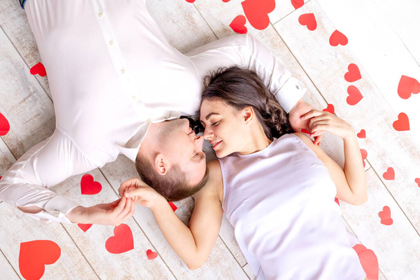 Ημέρα του Αγίου Βαλεντίνου, ένα ερωτευμένο ζευγάρι βρίσκεται ανάμεσα στις καρδιές στο πάτωμα αγκαλιάζοντας - Φωτογραφία, εικόνα