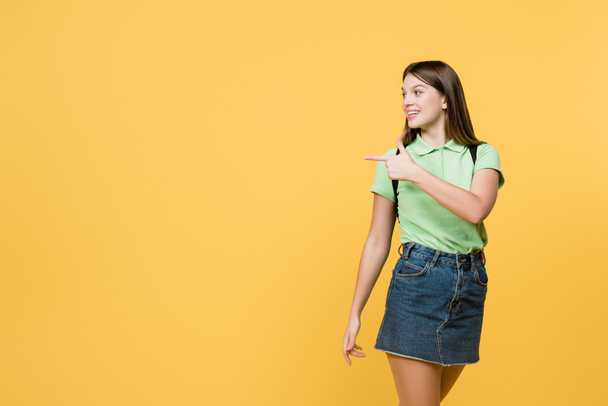 Cheerful teenager pointing with finger isolated on yellow - Fotoğraf, Görsel