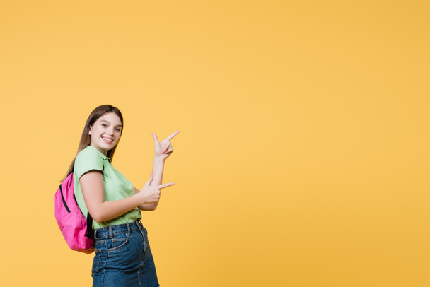 Cheerful teenager pointing with fingers isolated on yellow - Photo, Image