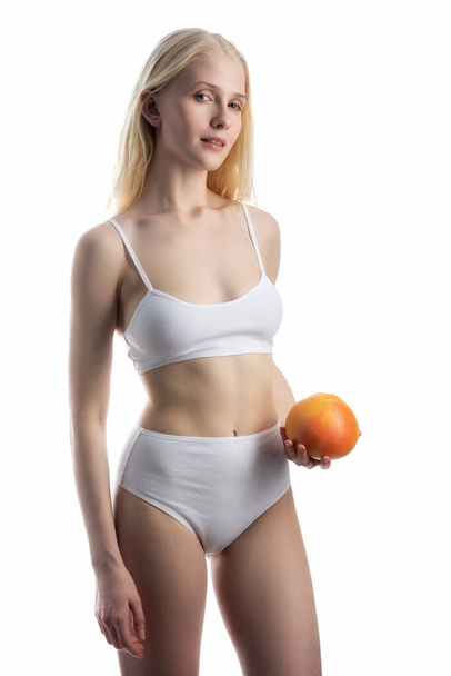 Closeup view of slim woman in underwear with orange on white background. - Photo, Image