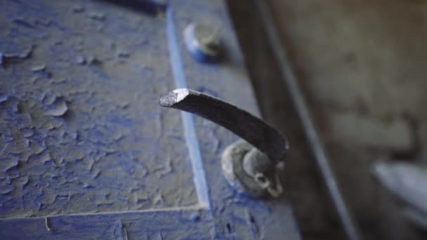 古いドアノブ。金属製のハンドルを持つ木製のドアはほこりで覆われている。無人の家だ。家に汚れた青いフロントドア。神秘的な場所. - 映像、動画