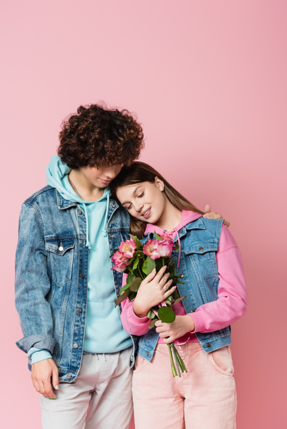 Hymyilevä teini tilalla kukkia lähellä poikaystävä eristetty vaaleanpunainen  - Valokuva, kuva