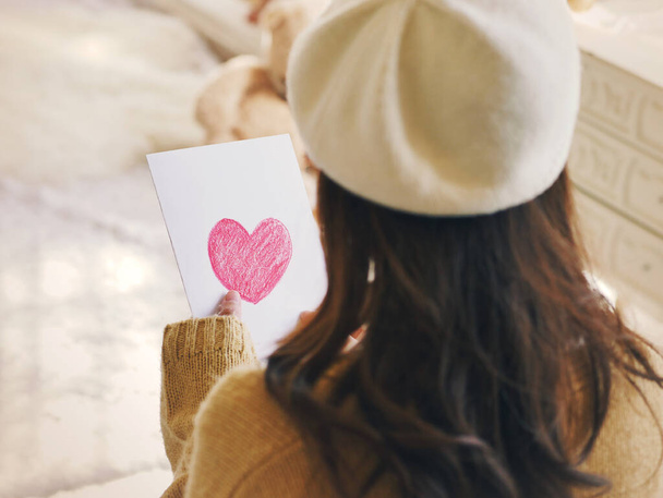 Las mujeres asiáticas miran la tarjeta con un corazón en la mano. - Foto, Imagen