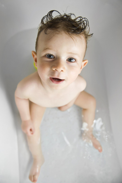 χαριτωμένο αγοράκι με αστεία μαλλιά μπάνιο στην μπανιέρα κοιτάζοντας το - Φωτογραφία, εικόνα