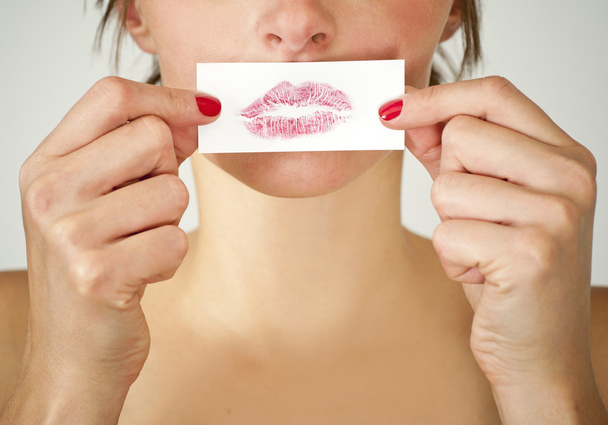 Attractive girl holding her lips print against her mouth.  - Φωτογραφία, εικόνα