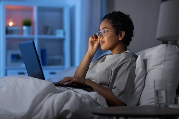 жінка з ноутбуком в ліжку вдома вночі
 - Фото, зображення