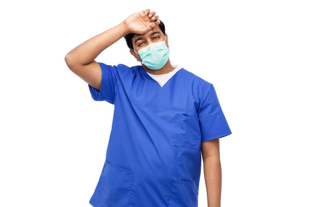 tired indian male doctor in blue uniform and mask - Valokuva, kuva