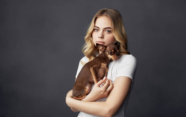 blonde holding a small dog pet friendship close-up - 写真・画像