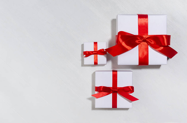 White gift different size boxes with red silk bow, ribbon on white wood table, top view, copy space, valentine's day background. - 写真・画像