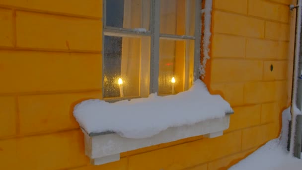 Świece w oknie pokrytym śniegiem. Piękna świąteczna atmosfera. Klasyczna architektura europejska. - Materiał filmowy, wideo