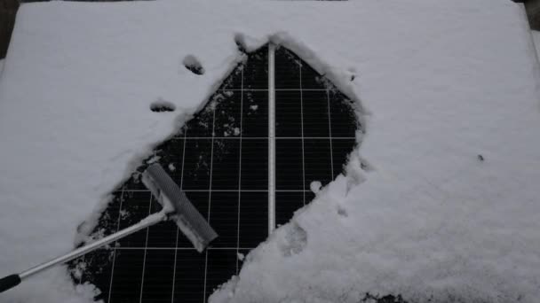 Removing snow from the solar panel. The solar element under the snow. Sun symbol. Cleaner solar cells generate more energy. - Footage, Video