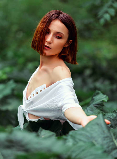 Beauty face woman bare shoulders behind green leaf plant. Portrait of caucasian woman's face surrounded by tropical leaves. Natural cosmetic, wellness, purity, skincare, beauty concept - Foto, Imagen