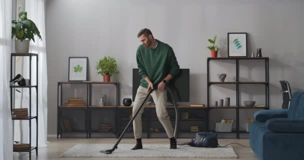 boldog srác porszívózik szőnyeg és tánc vicces a nappaliban, használ porszívó, szórakozás közben otthon takarítás - Felvétel, videó