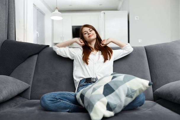 γυναίκα με μαξιλάρι σε άνετο καναπέ στο εσωτερικό του σπιτιού - Φωτογραφία, εικόνα