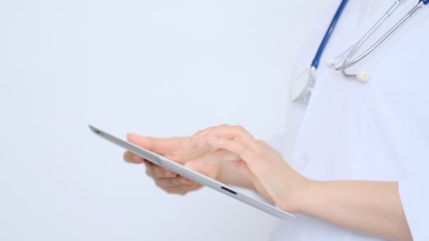 naislääkäri valkoisessa lab takki käyttäen modernia digitaalista tabletti pc. Online lääketieteen, terveyden tai lääketieteellisen verkoston käsite. Tablettitietokonetta käyttävät lääkärin kädet - Materiaali, video