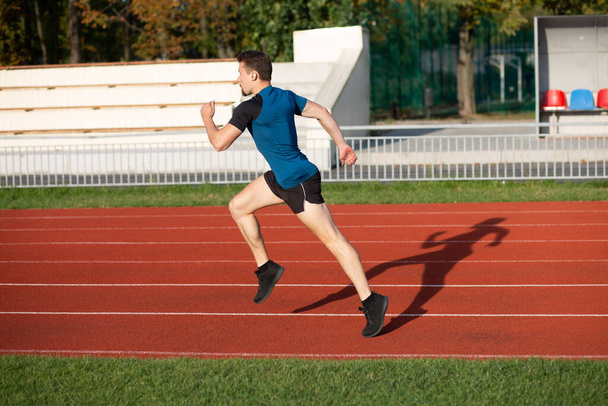 Gesunder junger, athletischer Mann beim Laufen im Stadion. Leere Räume - Foto, Bild