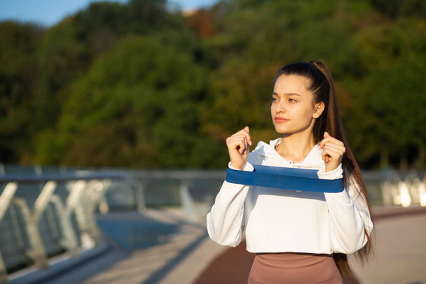 Femme sportive faisant de l'exercice avec une bande de fitness sur le pont. Espace libre pour le texte - Photo, image