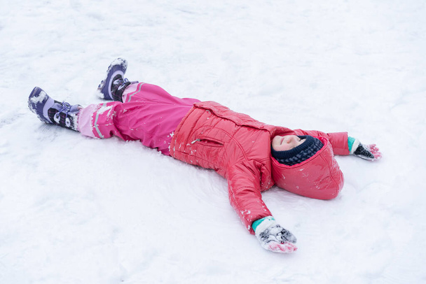 Το κοριτσάκι παίζει με το χιόνι. Χειμερινές διακοπές. - Φωτογραφία, εικόνα
