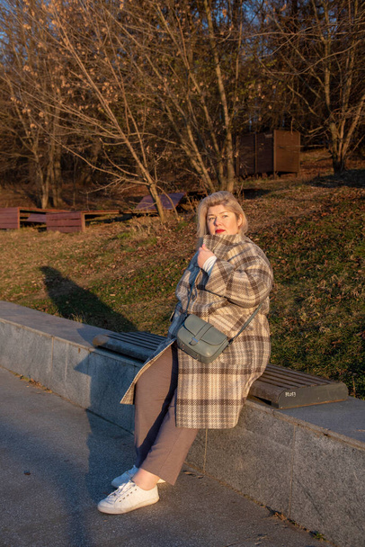 Portrait of a plump, middle-aged blonde woman walking in a park on a sunny late-autumn day. - Photo, Image