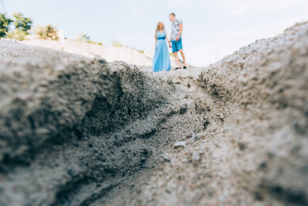 ライトブルーのドレスを着たブロンドの女の子とライトシャツを着た男と花崗岩の採石場での短いシャツ - 写真・画像