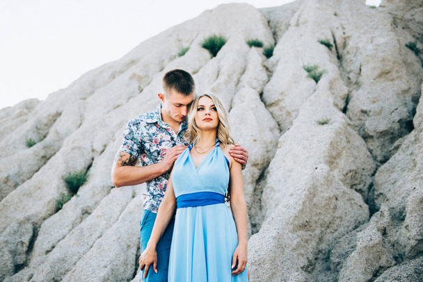 menina loira em um vestido azul claro e um cara em uma camisa leve e shert curto em uma pedreira de granito - Foto, Imagem