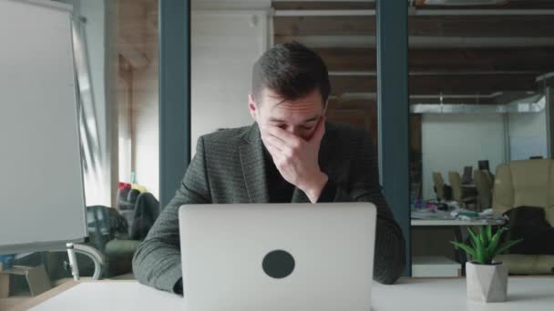 Allergiás fiatal üzletember az irodában. Beteg férfi öltönyben dolgozik laptop az irodájában, érzés tüsszent, és van egy orrfolyás, tünetei influenza és hideg. - Felvétel, videó