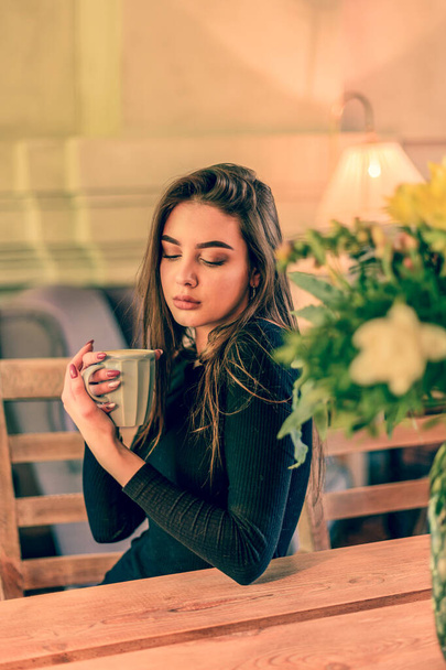 Mooie vrouw met kopje thee of koffie. Meisje met een kopje naar beneden kijkend. café, meisje, koffie, - Foto, afbeelding