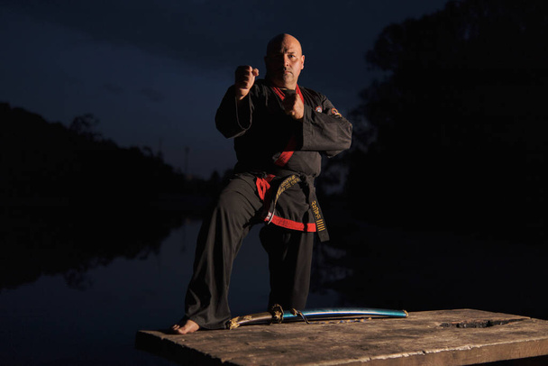 Sipalkido πλοίαρχος τη νύχτα με katana και ανάγνωση και μαύρη στολή - Φωτογραφία, εικόνα