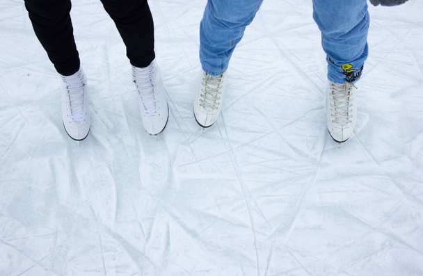 gros plan des pieds des femmes en patinage sur glace en hiver sur une patinoire extérieure. Patins à glace de deux amis patinant ensemble un jour d'hiver. Heure d'hiver, activités de plein air, concept de loisirs d'hiver - Photo, image