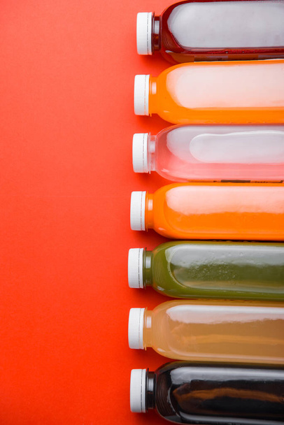 Photo of many detox fresh juice bottles in row over red background - Foto, Imagen