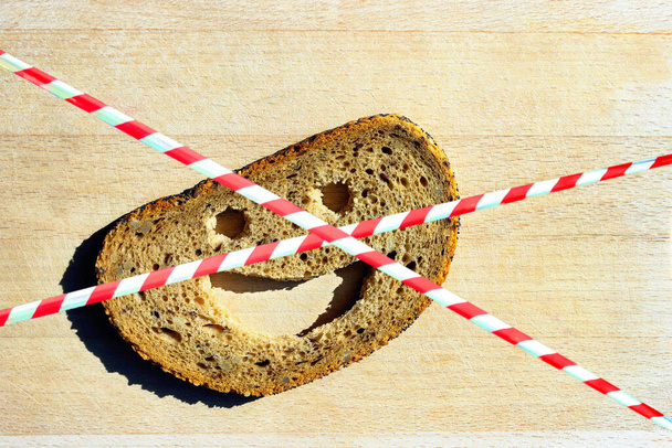 Barrier tape. Slice of rye bread with a smiling face. Concept-  allergy, intolerance, gluten-free.  - Photo, Image