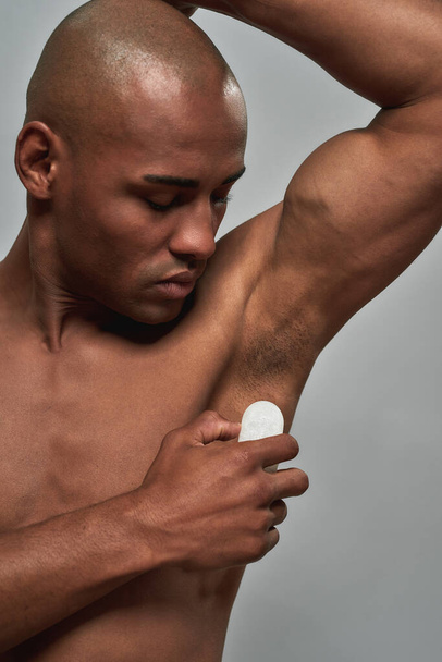 Athletic male running a crystal deodorant stone over armpit skin - Fotoğraf, Görsel