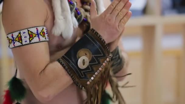 De sjamaan van sommige indianen stam in etnisch kostuum doet een ritueel op wild west festival. Close-up van een indiaanse Amerikaan wrijft zijn handen. Oud-Amerikaans erfgoedconcept - Video