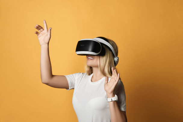 Blonde woman in t-shirt is VR glasses technology advanced user works in virtual reality pressing button. Side view - Photo, Image
