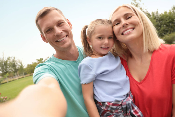 Happy family taking selfie in park on summer day - Fotoğraf, Görsel