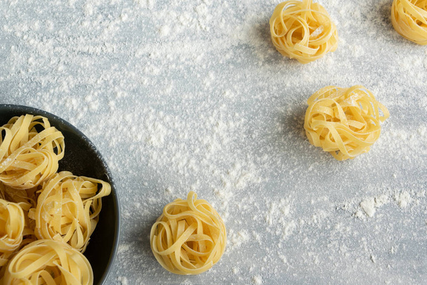 Handmade italian pasta - tagliatelle on grey floury background - 写真・画像