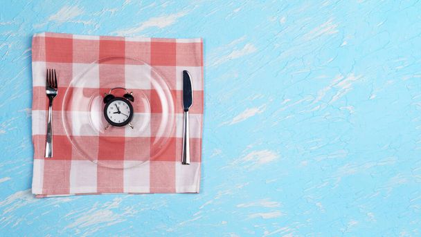 断続的な断食の概念,食事と減量.青い背景の目覚まし時計としてのプレート - 写真・画像
