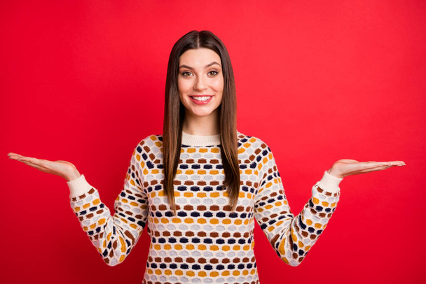 Portrait of optimistic nice girl hold empty space wear colorful sweater isolated on red color background - Φωτογραφία, εικόνα