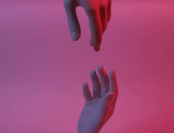 Руки Маннекіна простягаються один до одного червоним неоновим світлом. - Фото, зображення