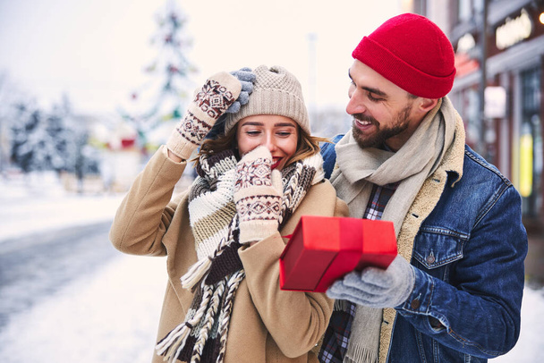 Cheerful woman getting surprise from boyfriend in snowy city - Foto, Imagem