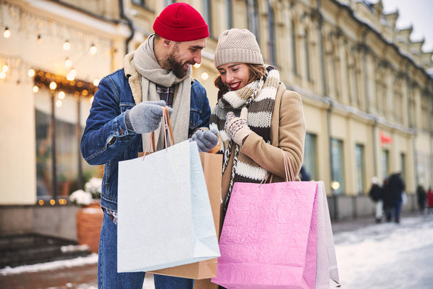 Χαμογελαστό ζευγάρι αγοράζοντας δώρα πριν τα Χριστούγεννα - Φωτογραφία, εικόνα