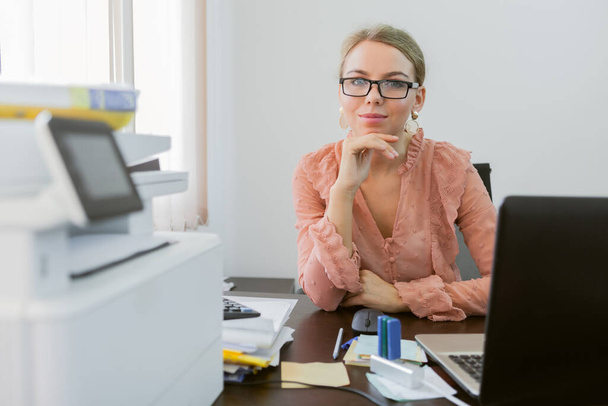 Die junge Geschäftsfrau sitzt an ihrem Arbeitsplatz im Büro und verwöhnt. Büroangestellte, Geschäftskonzept - Foto, Bild