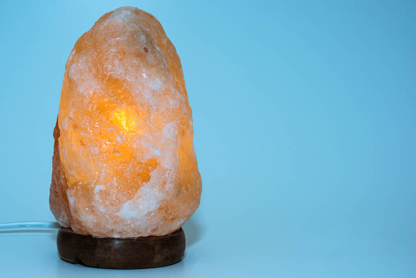 Glowing salt lamp on a blue background. - Photo, Image
