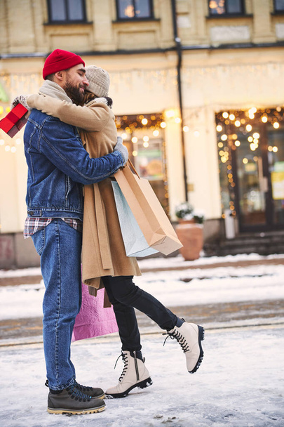 Joyful couple hugging in snowy city centre - Fotoğraf, Görsel