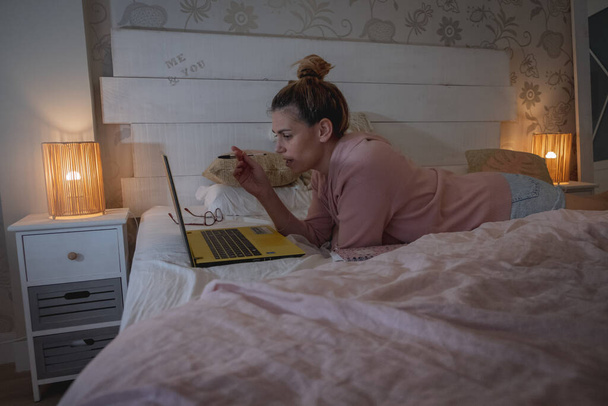 bonita chica rubia teletrabajo en habitación rosa con ordenador y portátil - Foto, imagen