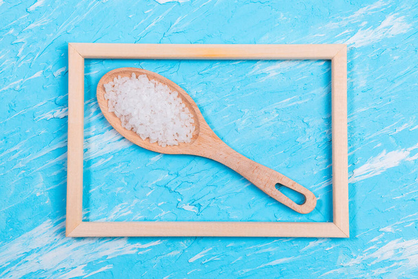 θαλασσινό αλάτι σε ξύλινη κουτάλα σε μπλε φόντο με χώρο για αντιγραφή κειμένου - Φωτογραφία, εικόνα