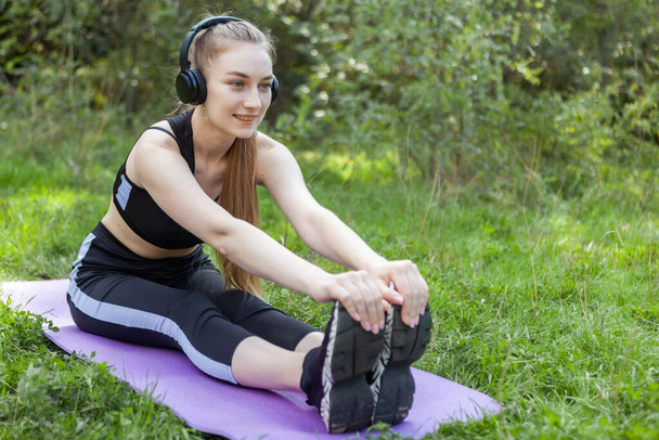 Active fit woman in sportswear stretching in the park at bright sunny day. Healthy lifestyle, fitness concept - Photo, Image